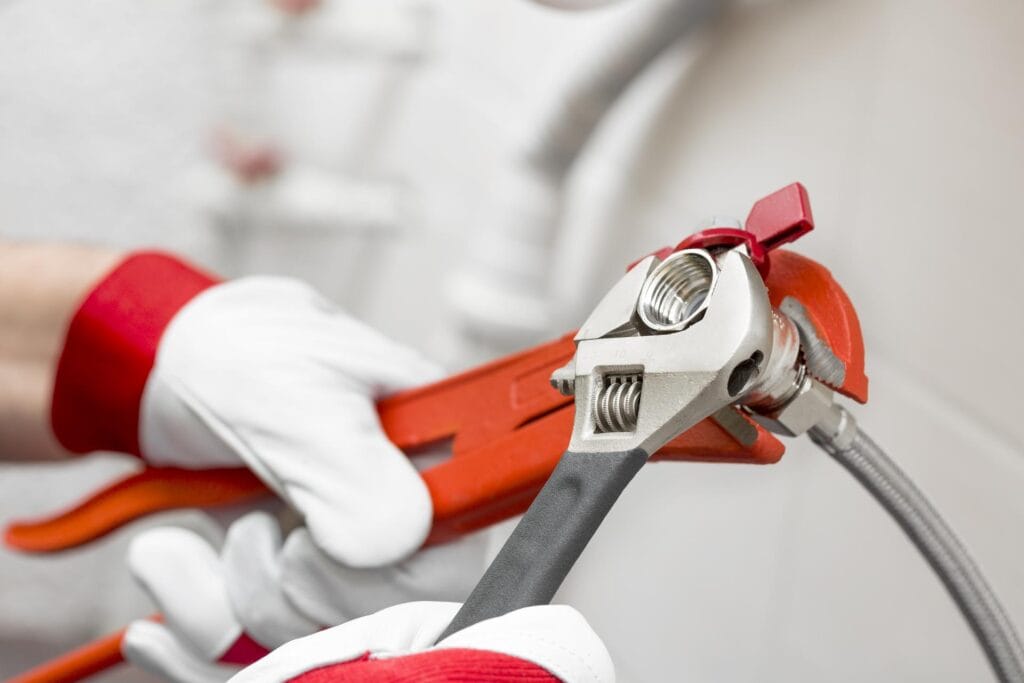 Plumber holding pipe wrenches for an emergency repair in Red Oak