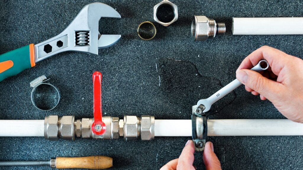 Plumber repairing a pipe valve with an adjustable wrench in Red Oak