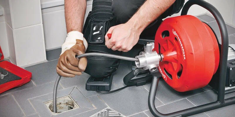 Plumber using a drain-cleaning machine in Red Oak