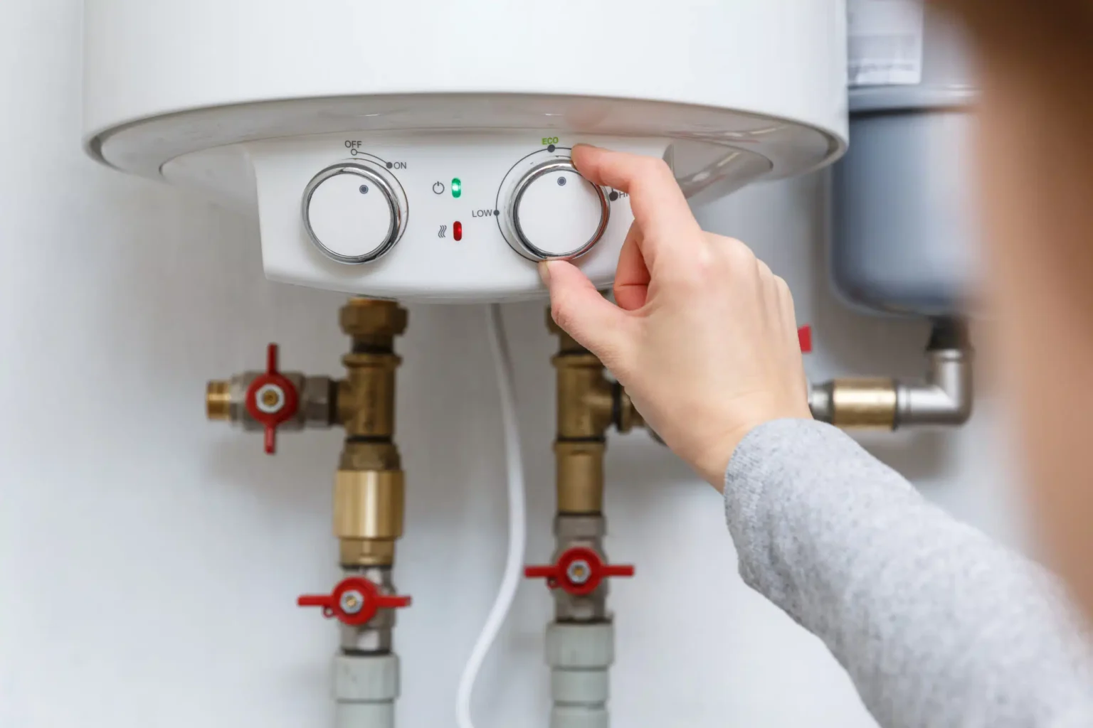 Homeowner adjusting the temperature controls on a water heater in Red Oak